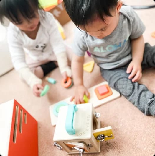 Two kids playing with toys from The Realist Play Kit